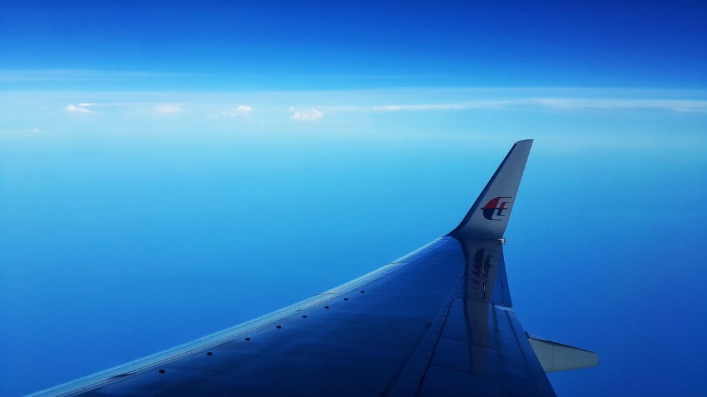 Airplane wing seen from window seat with blue sky background