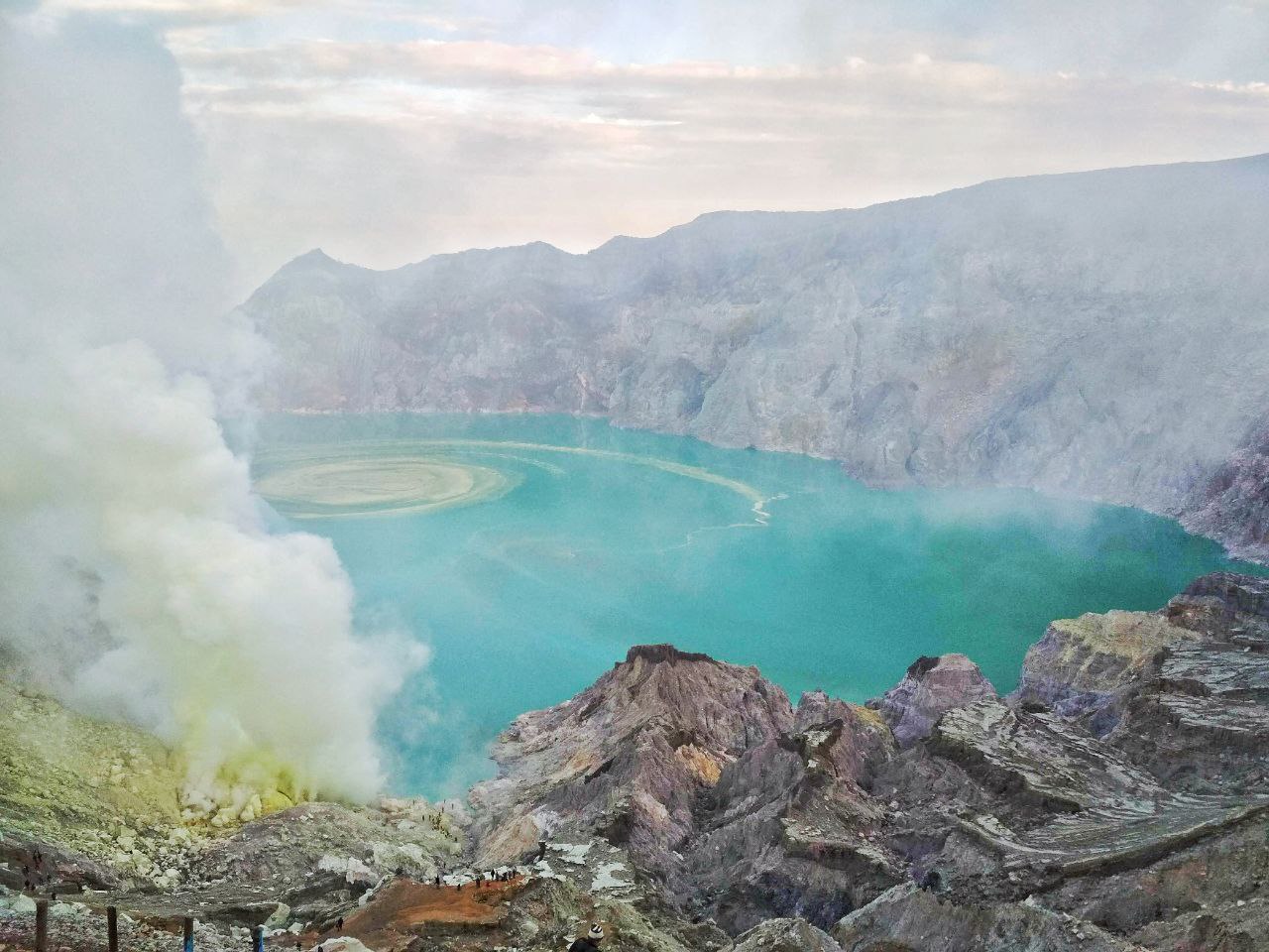 Sunrise view from Ijen Crater overlooking turquoise acidic lake in East Java